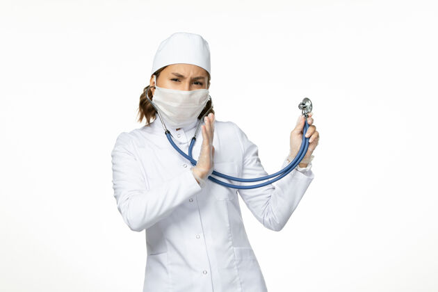 医疗器械正面图：年轻女医生戴着消毒口罩 因为白色桌子上有冠状病毒手持听诊器护士医疗持有