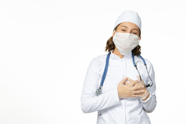 医疗正面图年轻女医生带着无菌口罩和手套由于冠状病毒在浅白的表面病毒面罩医疗器械