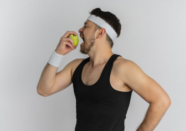 人一个戴着头巾的年轻人 手里拿着绿色的苹果 站在白色的背景上咬着苹果白苹果健身