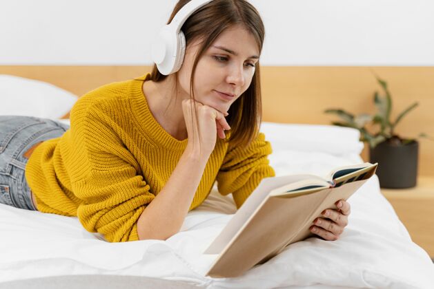 享受中枪女人在床上看书在家里乐趣耳机