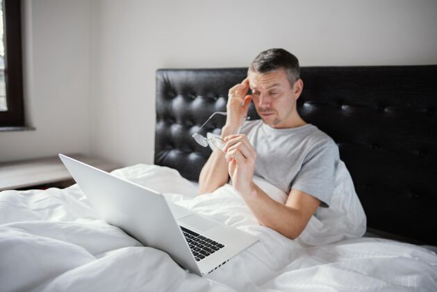 笔记本电脑男人在床上用笔记本电脑科技小玩意上瘾了