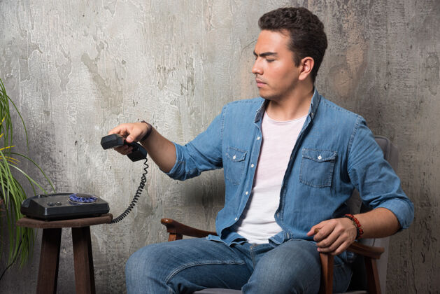 电话不满的男人拿着手机坐在椅子上高质量的照片人男男