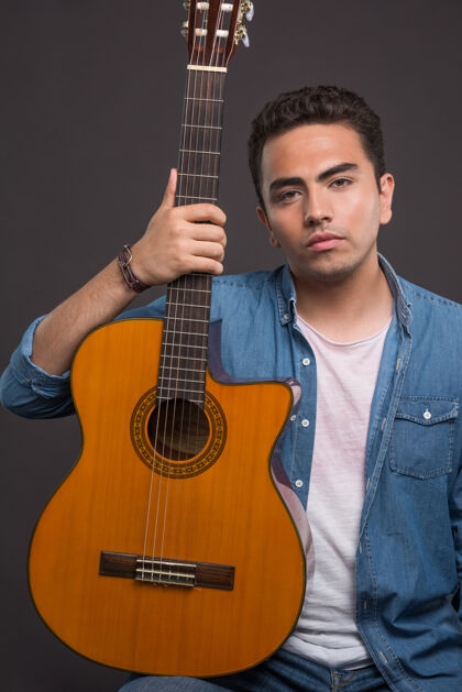 男年轻人拿着一把漂亮的吉他在黑色背景上高品质的照片人和弦乐器