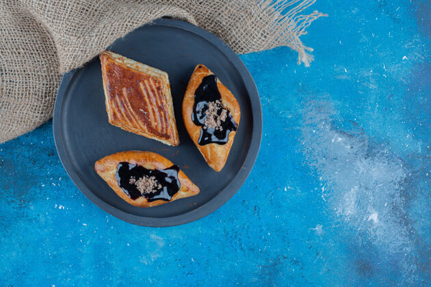 不健康的食物三块饼干放在毛巾旁边的木板上 蓝色背景高质量的照片美味甜点早餐