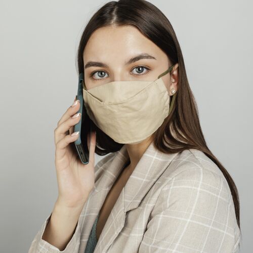 技术肖像时尚的女人用手机带面具电话冠状病毒手机