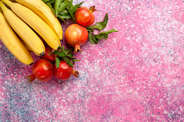 新鲜顶视图黄色香蕉和石榴在粉红色的表面食品有机醇香
