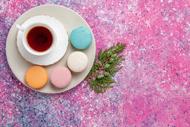 糖果顶视一杯茶 粉色表面有五颜六色的法国马卡龙生的派五颜六色