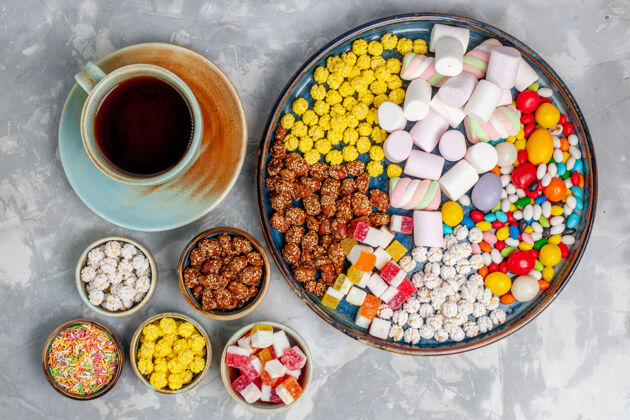 膳食顶视图糖果组成不同颜色的糖果与棉花糖和茶杯上的浅白色办公桌糖糖果邦邦甜封生的糖果棉花糖