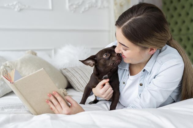 青少年特写女孩和可爱的狗在床上看书阅读青少年朋友