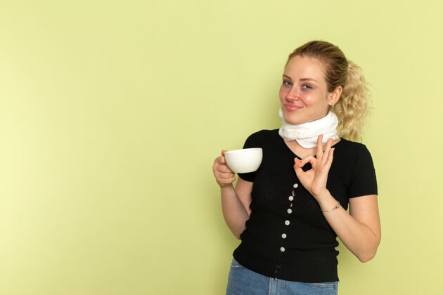 领带正面图年轻女性手捧一杯咖啡 微笑着坐在绿色的办公桌上生病生病生病咖啡生病举行