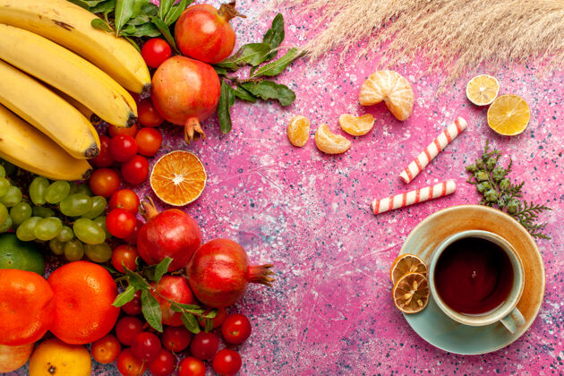 顶级顶视图新鲜水果组成与茶杯浅粉红色的表面生的杯子水果