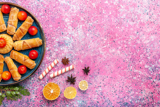 水疗顶视图-浅粉色桌上的甜甜可口的百吉饼和酸李子放在托盘里五颜六色李子桌子