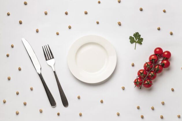 素食平铺的新鲜西红柿与盘子和餐具蔬菜养生刀