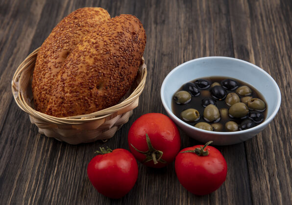 碗蓝色碗上新鲜橄榄的俯视图 桶上有馅饼 木制背景上有西红柿番茄橄榄肉饼