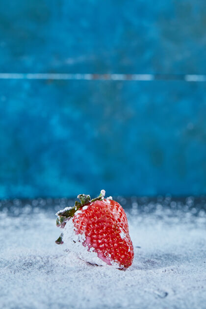 食物新鲜的红色草莓在蓝色的表面与粉末新鲜夏天多汁