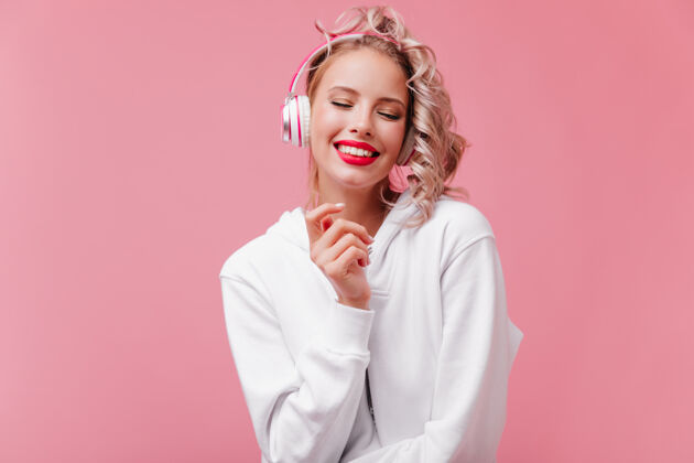 女性年轻女子摆姿势 通过她的粉红色耳机听音乐可爱爱情舞蹈