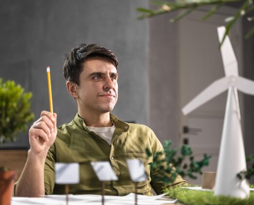 工程师人类正在思考一个带有风力涡轮机的环保风力发电项目的正面图工作铅笔环保