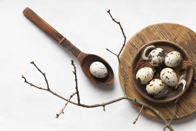 盘子用勺子和树枝把复活节彩蛋平放在木盘上节日节日鸡蛋