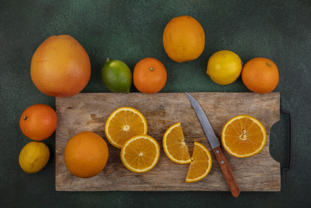 葡萄柚俯视图切割板上的橙色切片与刀柠檬酸橙和葡萄柚绿色背景刀酸橙顶部