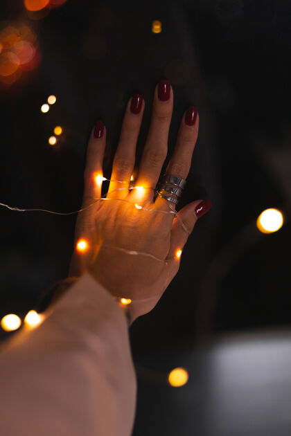 明亮的光美丽的黑色照片的妇女手指头与大银戒指上的花朵和发光的灯光美容美甲奢侈品