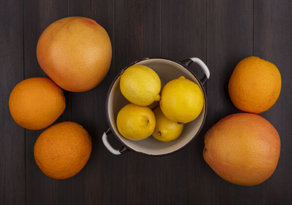 柑橘顶视图葡萄柚与橙子和柠檬在平底锅上的木头背景新鲜橘子食品
