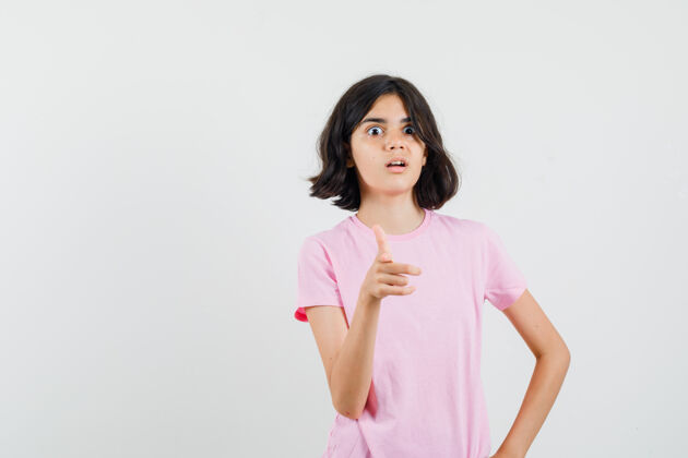 可爱小女孩指着前面的粉红色t恤衫 看起来很困惑 前面的看法时尚青少年困惑