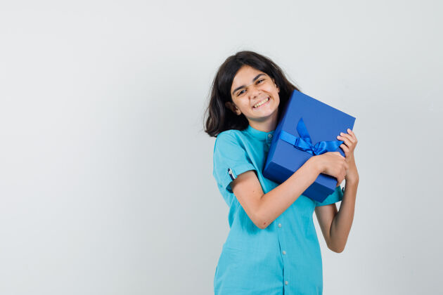 年轻十几岁的女孩抱着她的礼物盒在蓝色衬衫 看起来很高兴时尚肖像欢呼