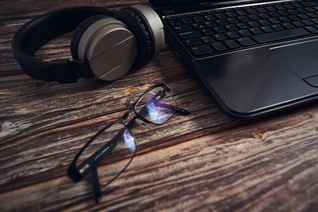 视图把笔记本电脑眼镜和耳机放在木桌上桌子工作工作区