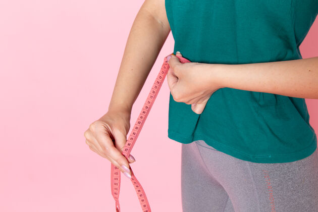 锻炼前视年轻女性抱腰量浅粉色书桌美女运动锻炼运动员锻炼苗条测量运动女性