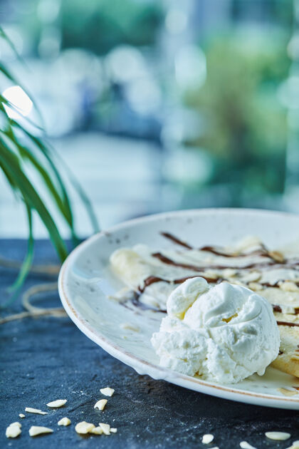 盘子薄饼加冰淇淋 洒上巧克力 放在白色盘子的深色表面植物甜的冰淇淋