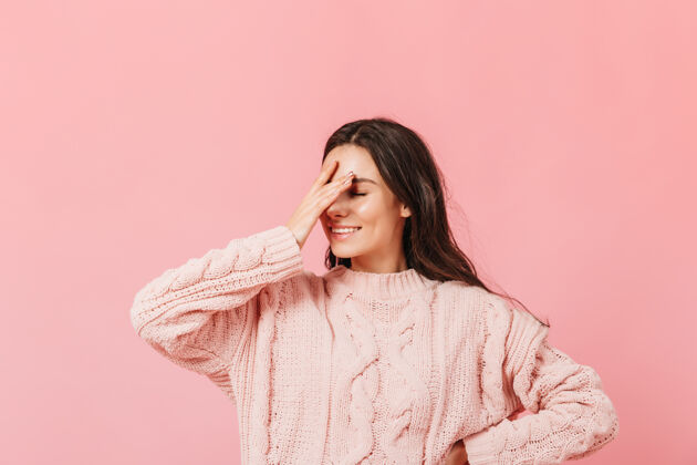 女孩穿着粉色毛衣的女人在孤立的背景上摆姿势笑着的有趣女孩做了个脸掌女性毛衣套头衫
