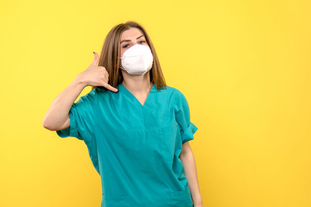 女医生黄色大流行医院地板上戴着面罩的女医生的正视图快乐正面肖像
