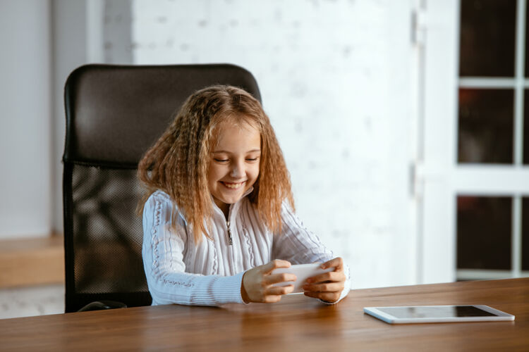 完美年轻的白人女孩的肖像看起来梦幻 可爱和快乐抬头看 坐在室内的木桌与平板电脑和智能手机未来的概念 目标 梦想购买 可视化休闲梦想漂亮