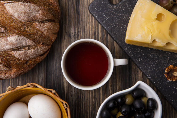杯子俯瞰一杯茶 放在架子上 上面放着橄榄和黑面包顶早晨茶