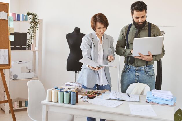 服装师时装设计师用笔记本电脑在工作室工作的前视图商务裁缝裁缝