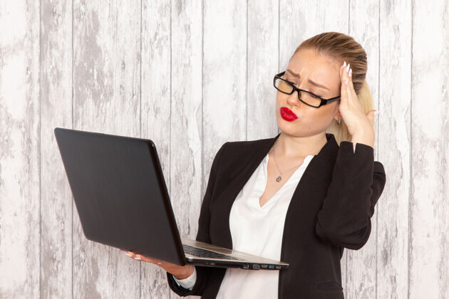 女商人正面图年轻女商人穿着严苛的衣服黑色夹克在白墙上用笔记本电脑上班上班上班女商人专业人士观点笔记本电脑