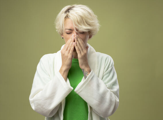 短裤一个短头发的生病的女人站在光墙上用餐巾擦鼻子疾病女人湿巾