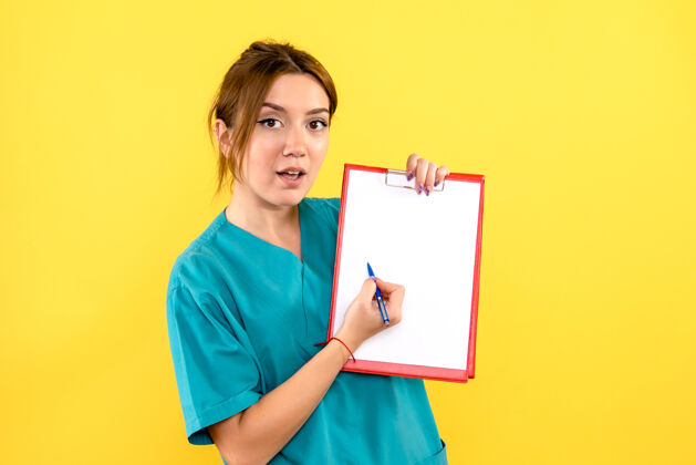 前面女兽医在黄色墙上写笔记的正视图成人女士快乐
