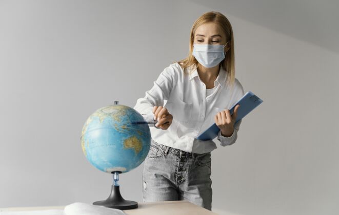 地球仪教室里女教师的正视图 剪贴板指向地球流行病新常态返校