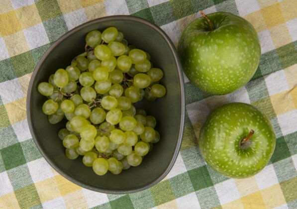 顶部俯瞰黄绿色格子毛巾上的绿色葡萄和绿色苹果景观葡萄绿色