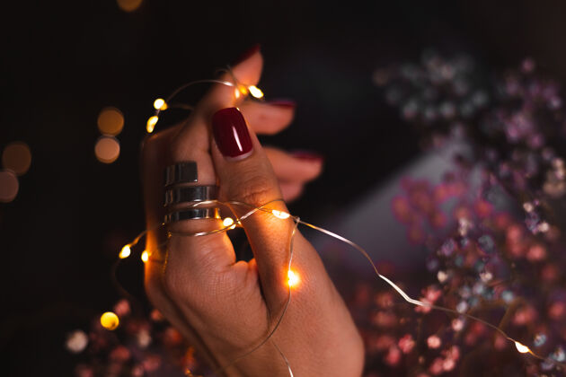 手指美丽的黑色照片的妇女手指头与大银戒指上的花朵和发光的灯光模型指甲奢侈品