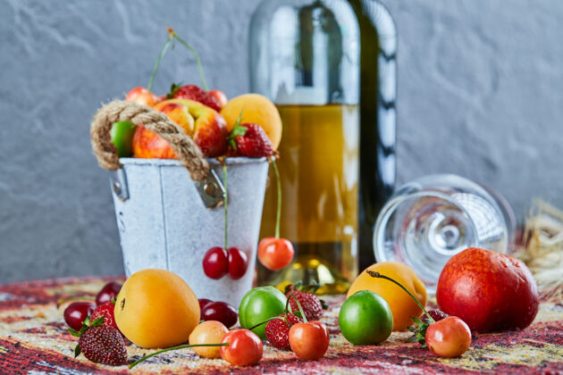瓶子一桶新鲜的夏日水果 一瓶白葡萄酒 一个空杯子放在雕刻的地毯上玻璃杯饮料餐桌