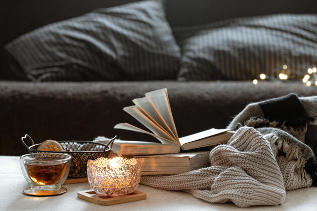 房子静物与一杯茶 书籍和燃烧的蜡烛在一个美丽的烛台家居舒适的概念茶模糊的背景烛台
