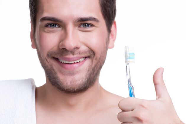 大拇指朝上？？？一个戴着牙刷的快乐的年轻人的失传肖像-孤立在白色上牙齿男人卫生