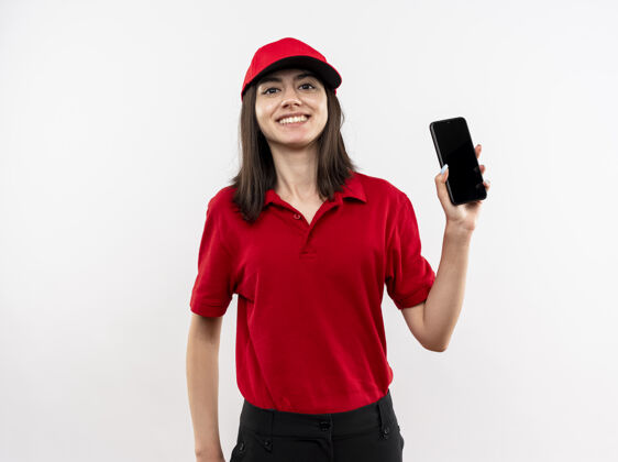 帽子年轻的送货员身穿红色制服 戴着帽子 站在白色的墙上 脸上露出愉快的笑容送货微笑看