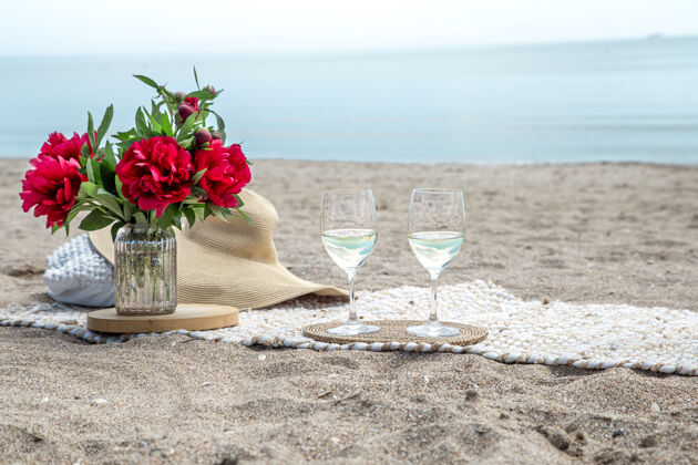 浪漫带着鲜花和香槟的海边浪漫野餐度假的概念饮料夏天海滩