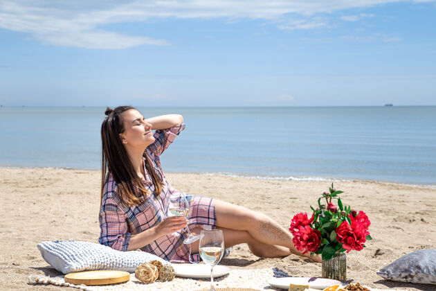 花一个女孩在沙滩上休息在沙滩的沙滩上浪漫的野餐暑假的概念优雅夏天美丽