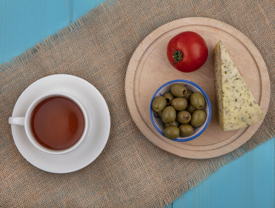 杯子在米色餐巾纸上放一个茶座 上面放着一杯芝士橄榄和西红柿米色早晨橄榄色