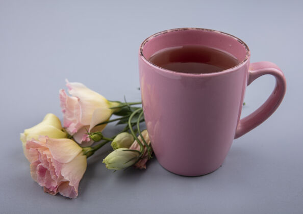 茶一杯粉红色的茶的顶视图 灰色背景上有鲜花桌子新鲜马克杯
