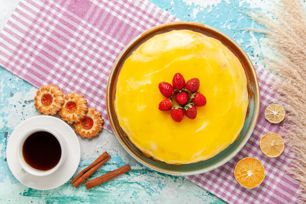 视图俯瞰美味的蛋糕 黄色糖浆和新鲜的红色草莓放在浅蓝色的饼干蛋糕上 烤甜甜的糖派茶早餐草莓生的